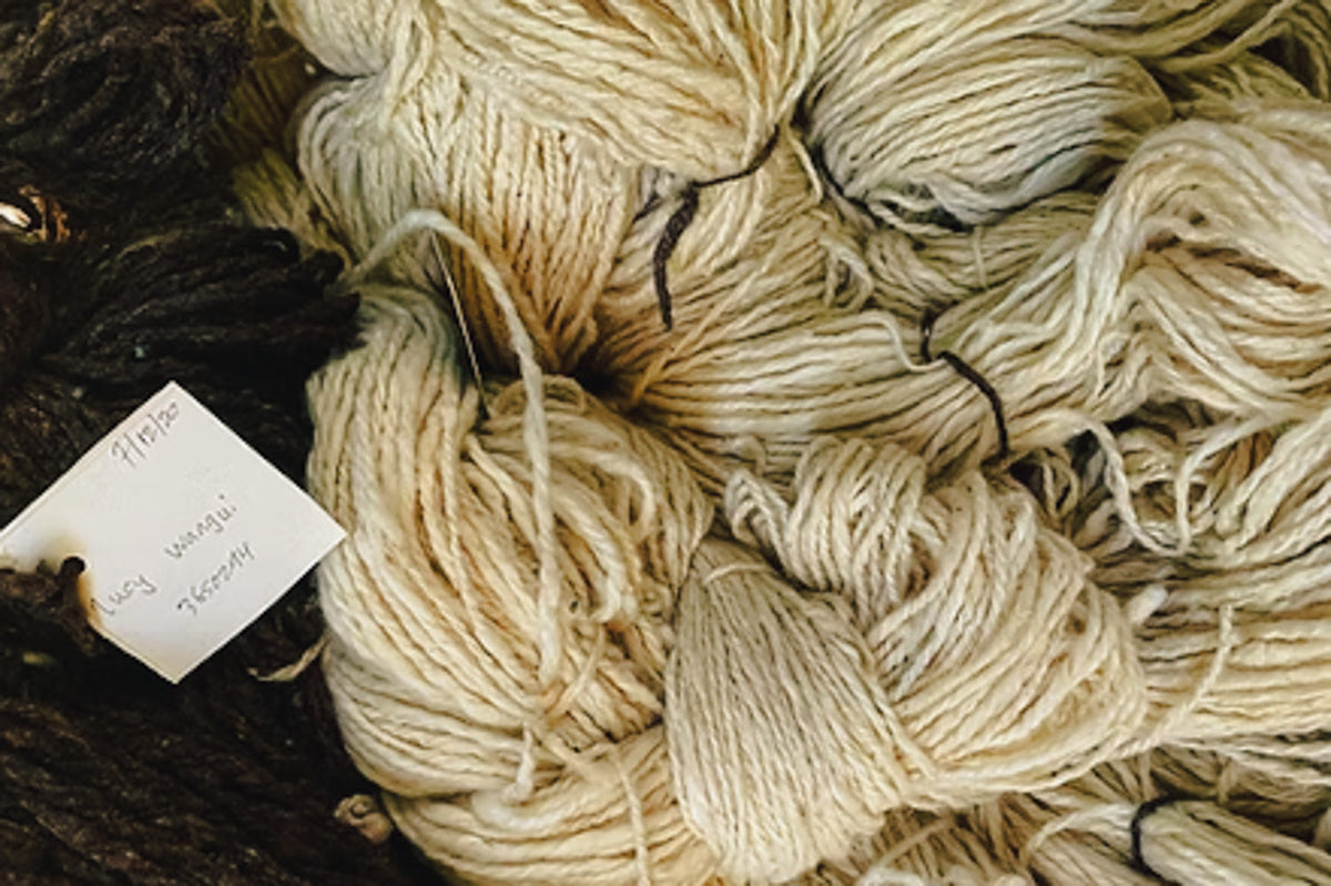 Close-up of beige yarn with a tag labeled 'flaxen' on a dark background