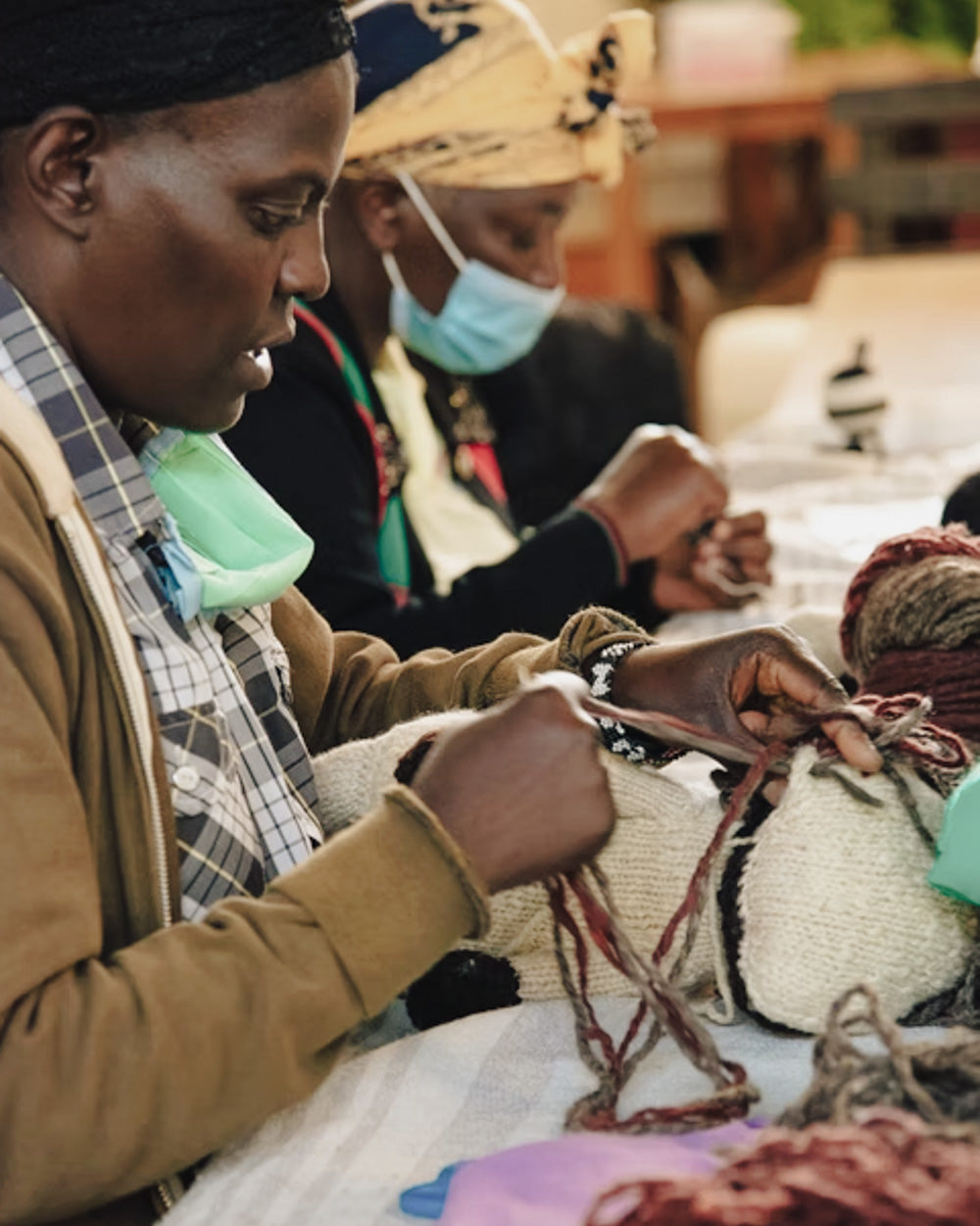 Two people working on a craft project with yarn at a table.